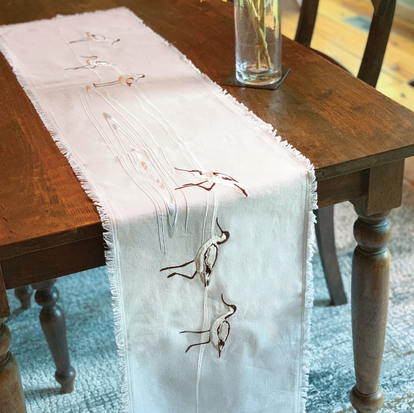 Avocets wading in waves embroidered table runner with fringe.