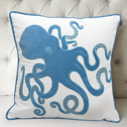 Blue Inkling Octopus indoor pillow styled on a tufted gray couch.