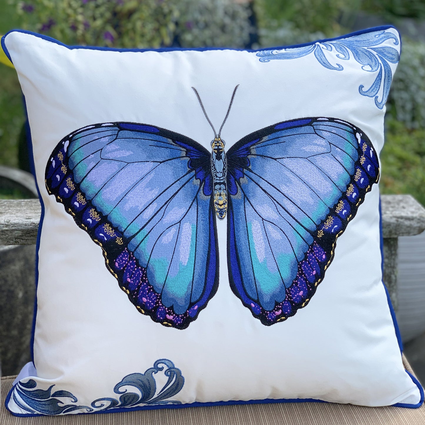Bold Blue Butterfly outdoor pillow styled on a bench.