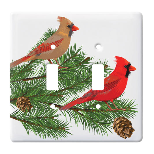 ceramic double toggle switch plate featuring two cardinals sitting upon a pine tree branch. 