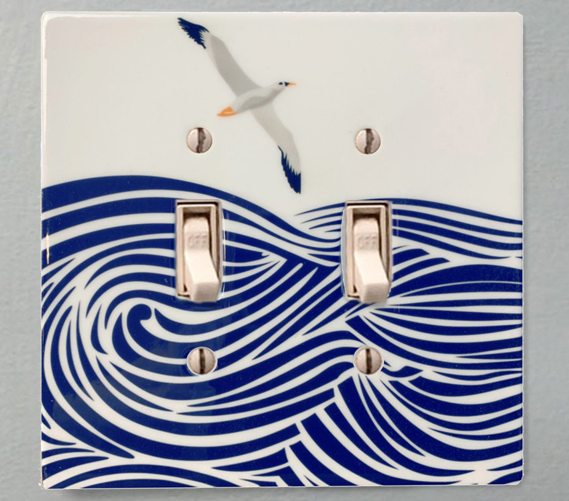 ceramic double toggle switchplate featuring illustration of albatross flying above waves.