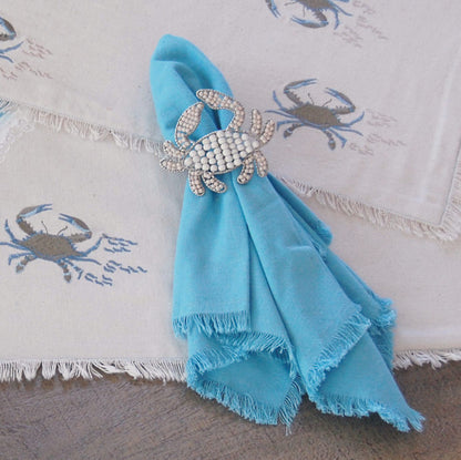 Crab shaped napkin rings crafted of natural beads around a blue napkin.