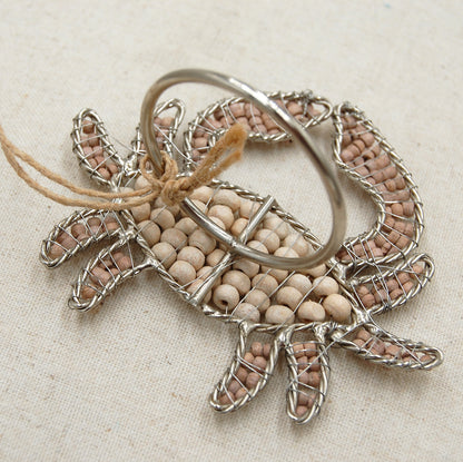 Back side of crab shaped napkin rings crafted of natural beads.