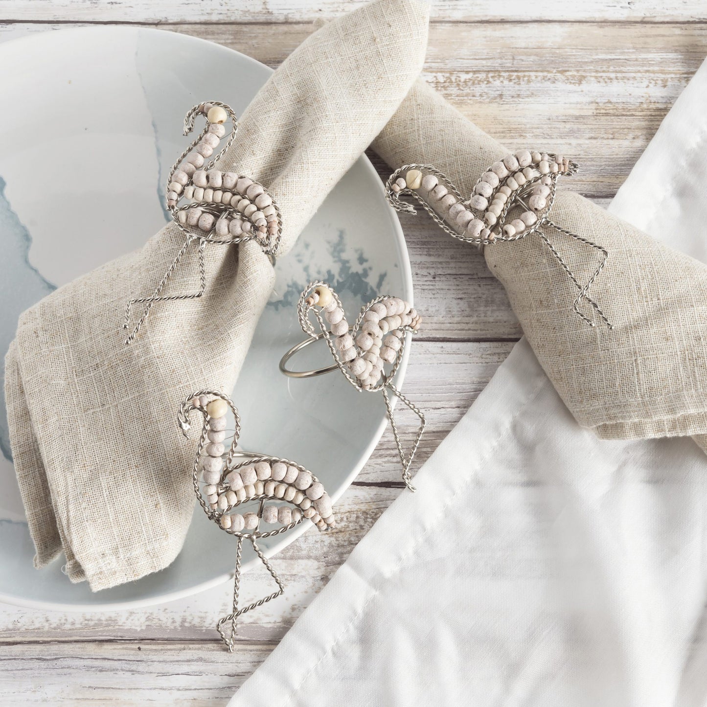 4 flamingo shaped napkin rings constructed of natural wooden beads and wire for the legs.