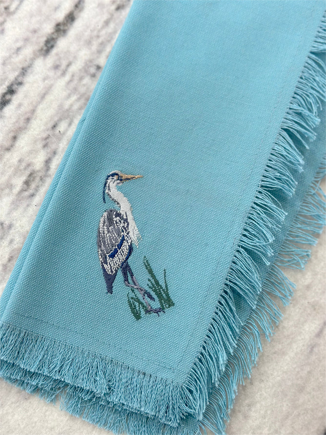 Blue Heron embroidered on blue cotton fabric with fringe edge.