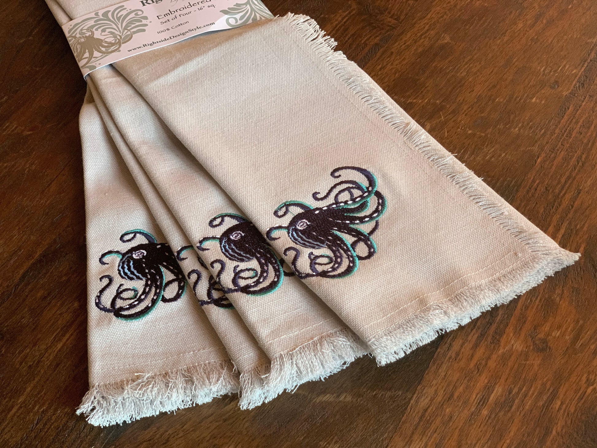 Navy octopus with teak tentacles embroidered on fringed grey cotton napkins.