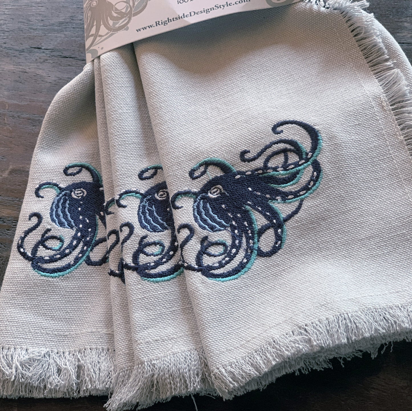 Navy octopus with teak tentacles embroidered on fringed grey cotton napkins.