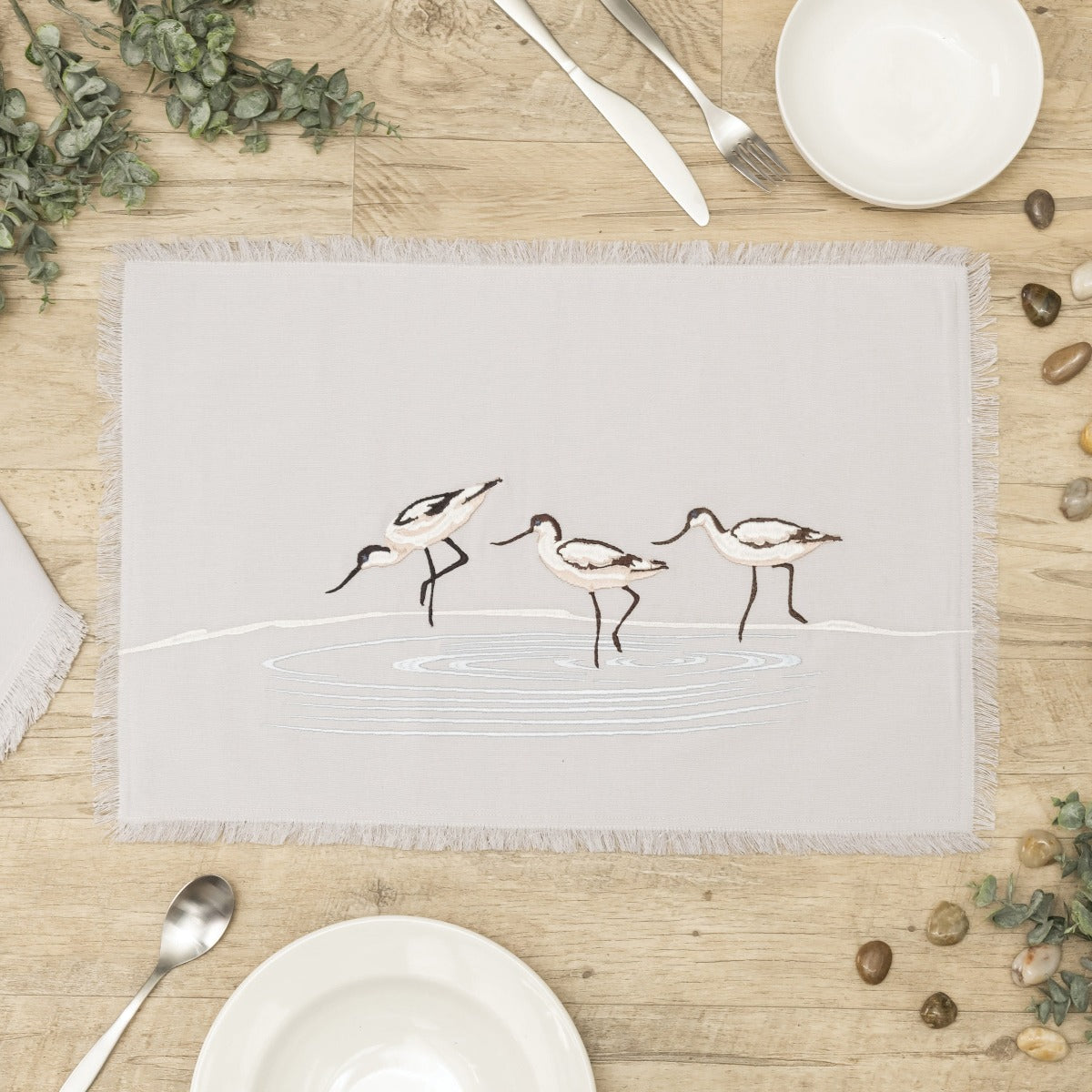 Avocets wading in waves embroidered placemat with fringe.