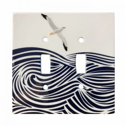 ceramic double toggle switchplate featuring illustration of albatross flying above waves. 