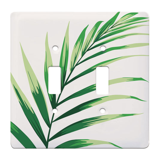 ceramic double toggle switchplate featuring illustration of green arcea palm leaf. 