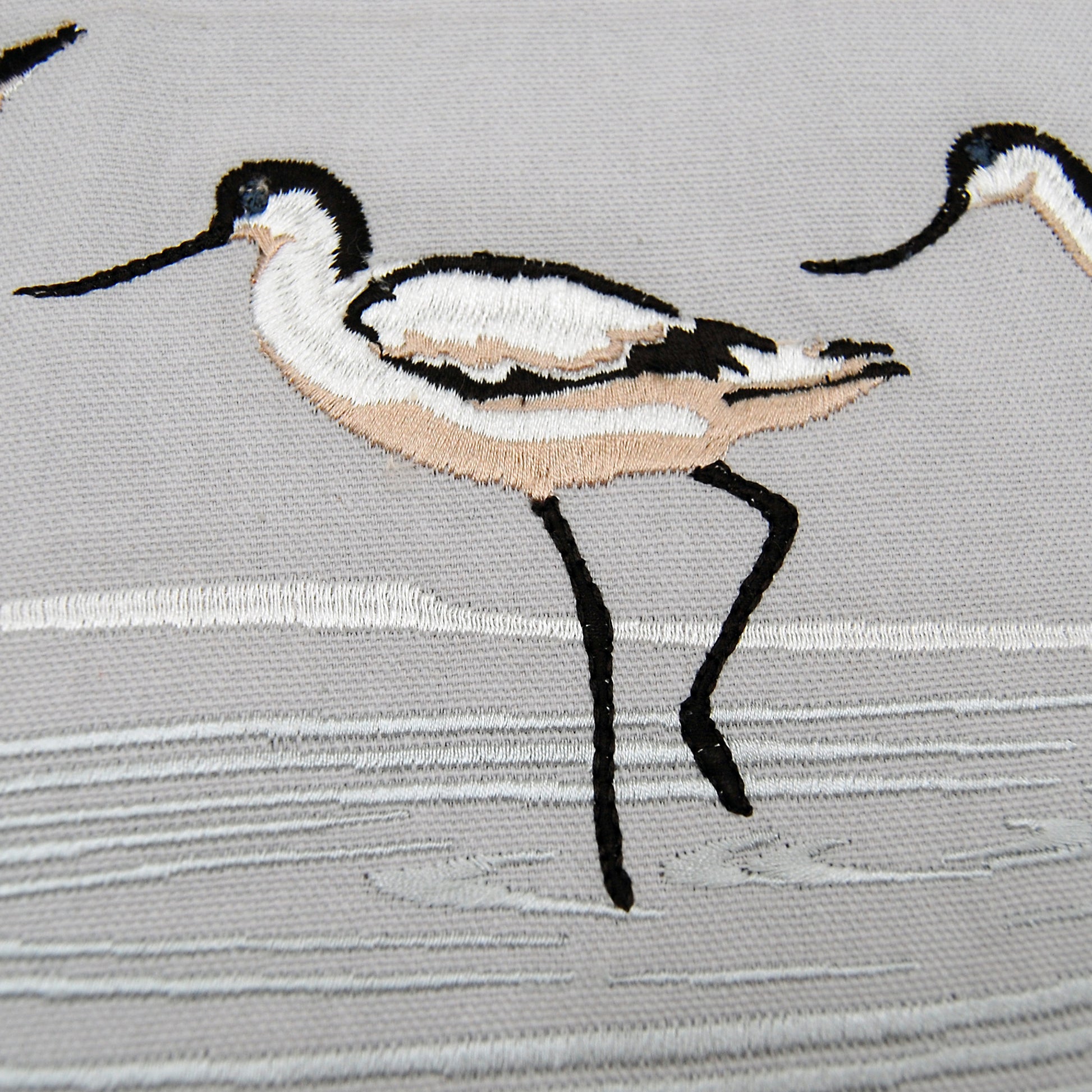 Detailed shot of the embroidery on the Avocet Fringed Lumbar pillow.