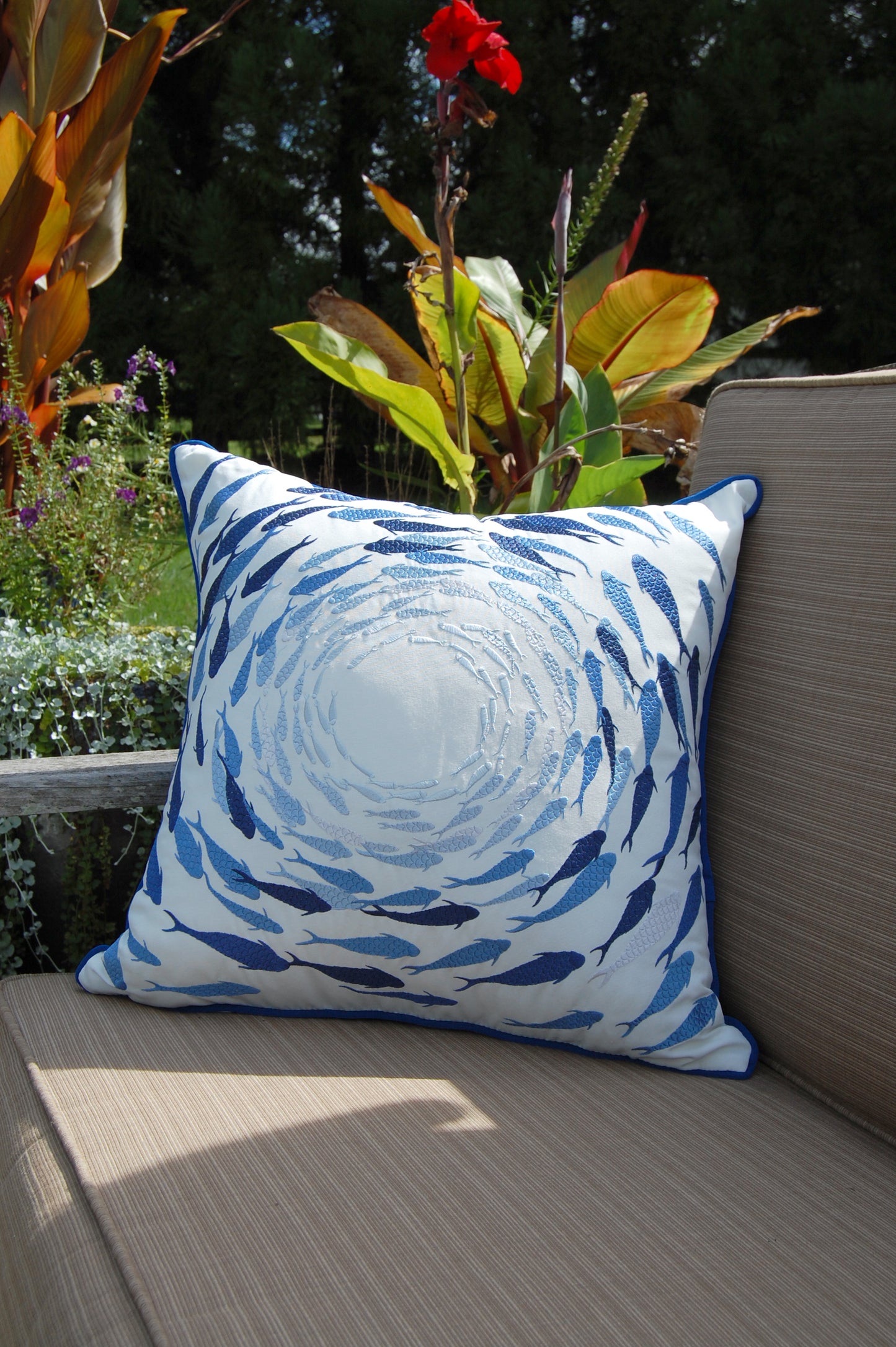 Azure Fish School outdoor pillow pictured on a patio couch.