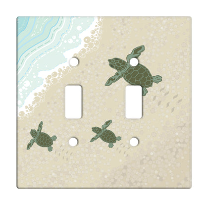 ceramic double toggle switchplate featuring baby turtles moving across sand to the ocean. 