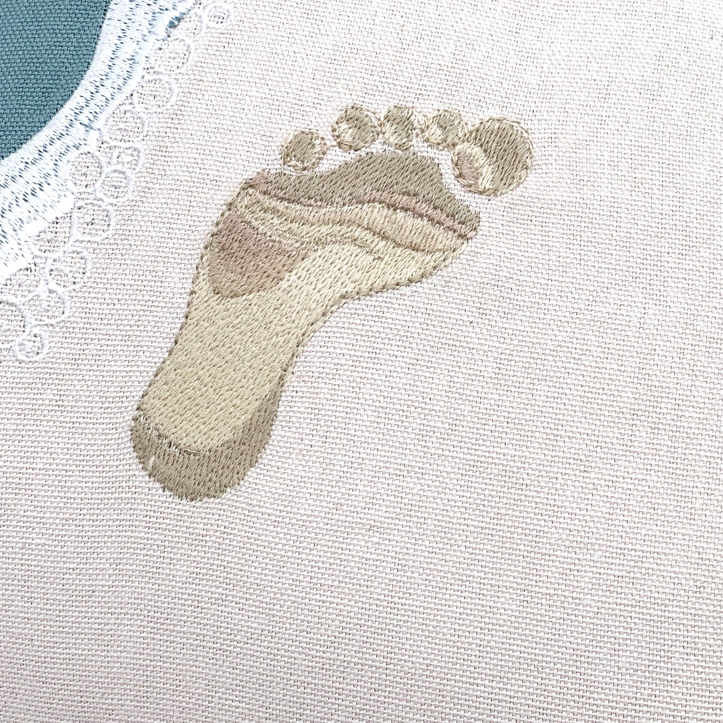 Detail shot of the embroidery work on the Best Friends Footprints Lumbar Pillow.