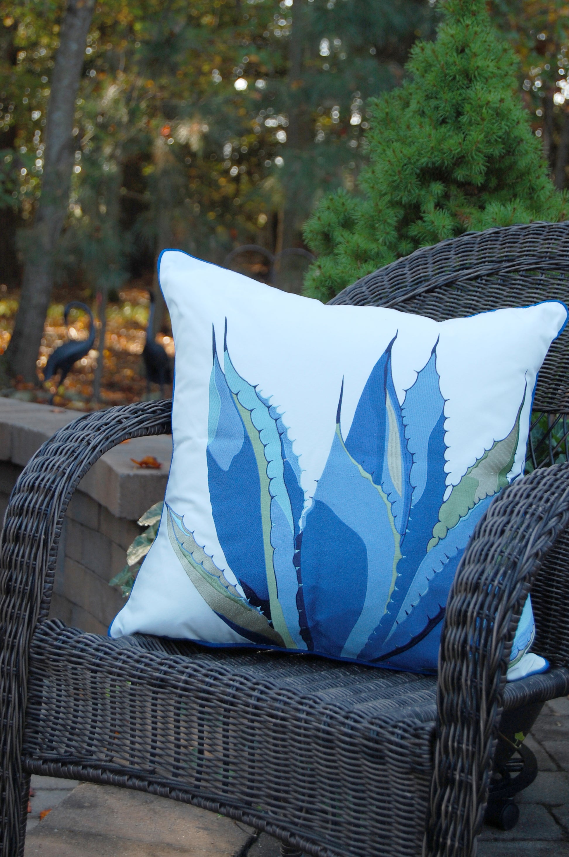 Blue Agave Indoor Outdoor pillow styled on a wicker chair.