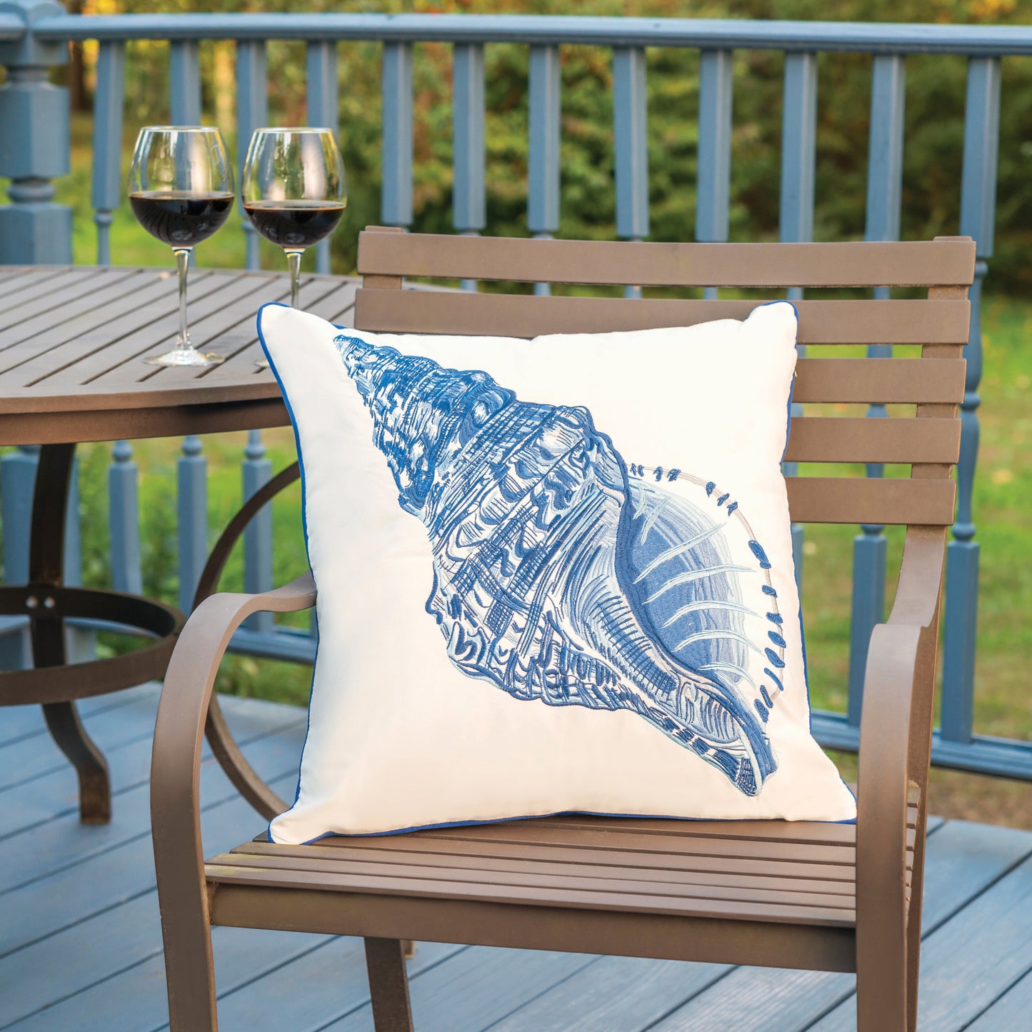 Blue Conch Shell pillow styled on an outdoor patio chair.