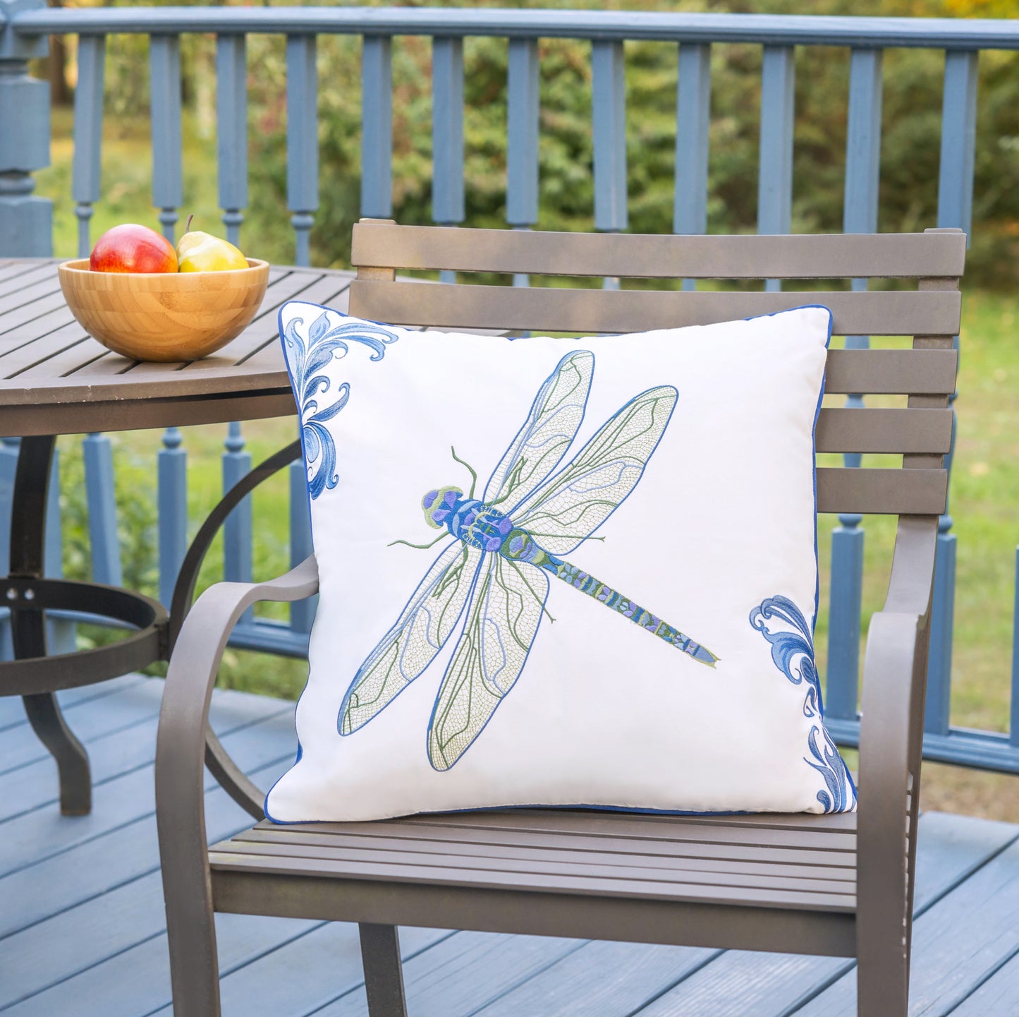 Blue Dragonfly outdoor pillow styled on an outdoor patio chair.