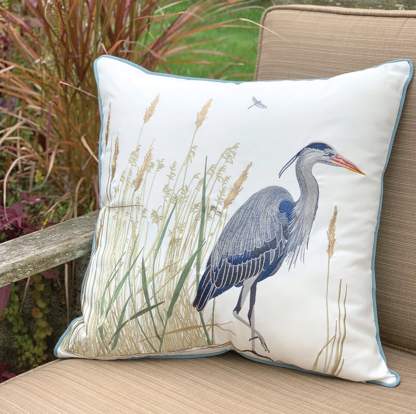 Blue Heron and Saltmarsh outdoor pillow styled on a patio chair.