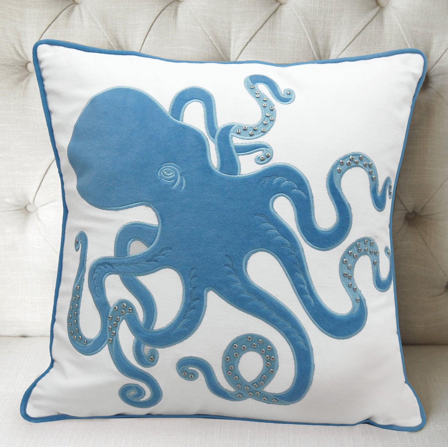 Blue Inkling Octopus indoor pillow styled on a tufted gray couch.