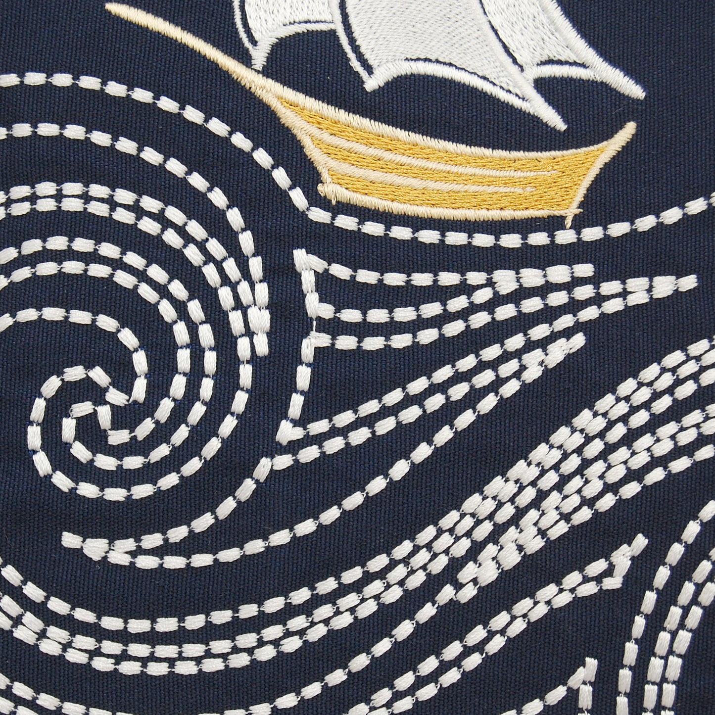 Detail shot of the embroidered sail boat and waves on the Cape Series Stormy Seas pillow.
