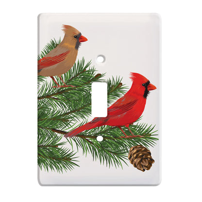 ceramic single toggle switch plate featuring two cardinals sitting upon a pine tree branch. 