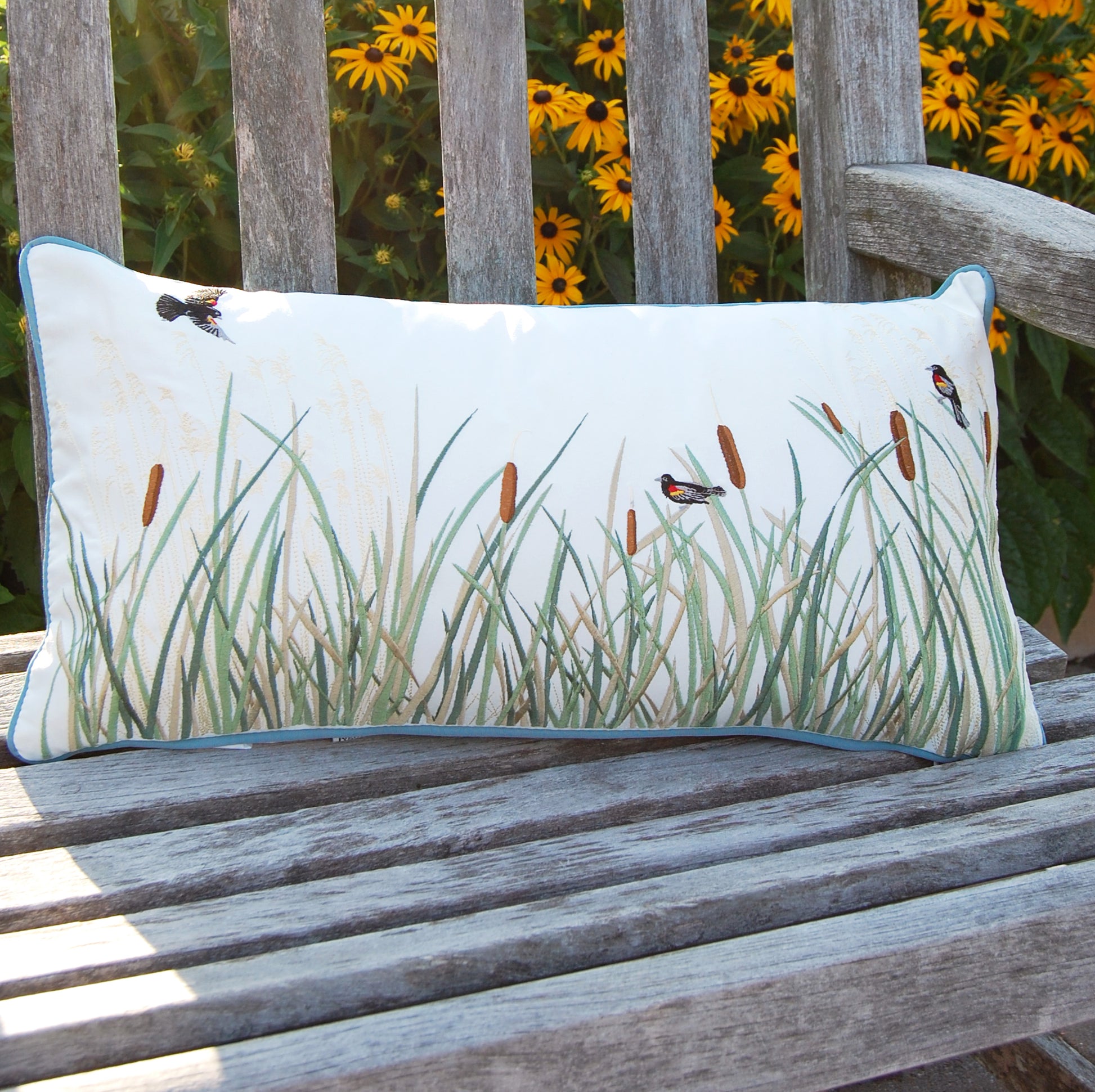 Cattails and Red Winged Blackbird pillow styled on an outdoor bench.