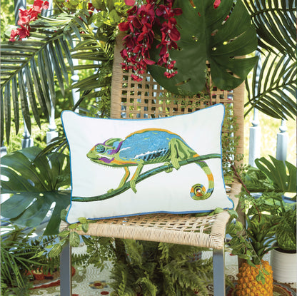 Chameleon outdoor pillow styled on a jute chair, surrounded by tropical plants.