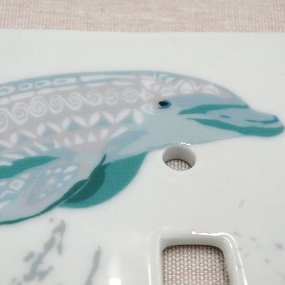 Detail shot of the porcelain Tribal Dolphins switch plate