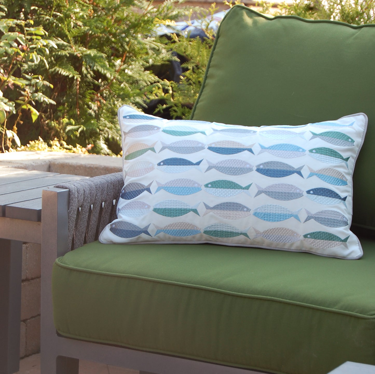 Fish Pattern pillow styled on a green patio couch.