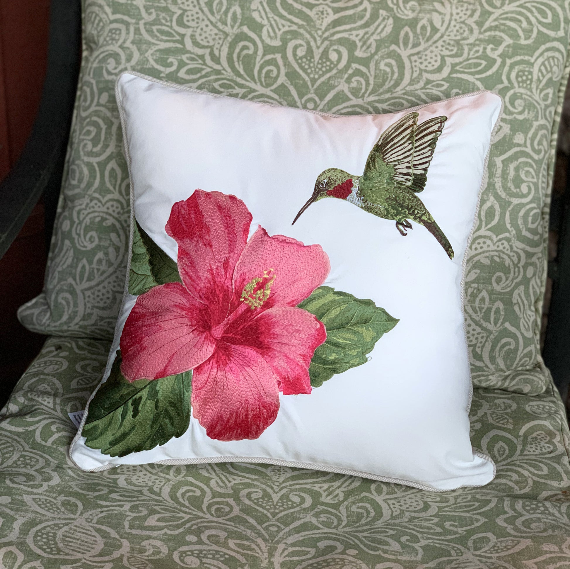 Hummingbird and Hibiscus pillow styled on an outdoor chair.