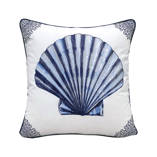 Large blue scallop shell embroidered on a white background. Scroll designs frame the pillow in each corner.