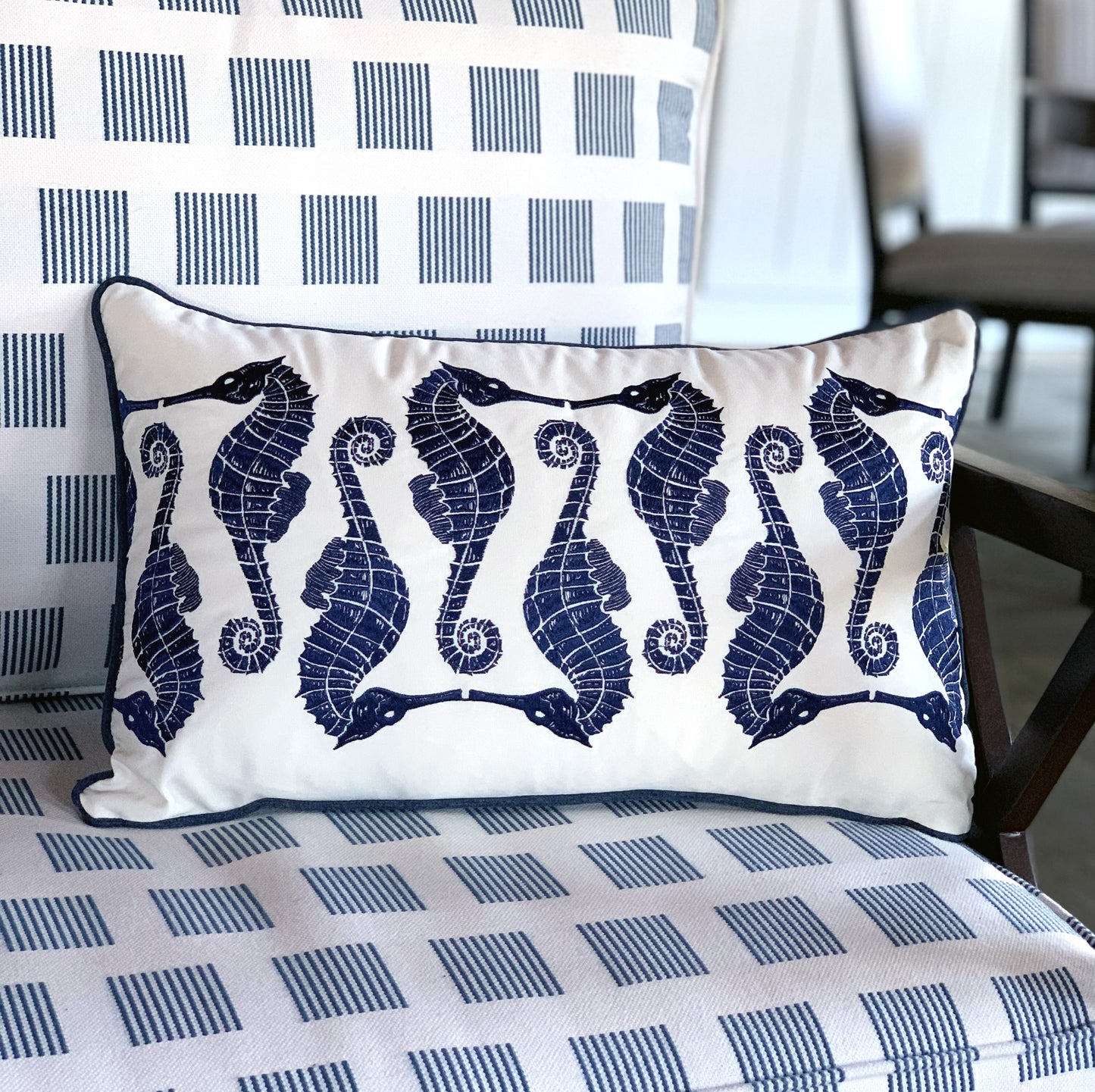 The Indigo Seahorse Outdoor Pillow styled on a patio chair.
