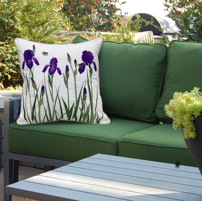 The Iris and Bee Indoor Outdoor Pillow styled on a green patio sofa.