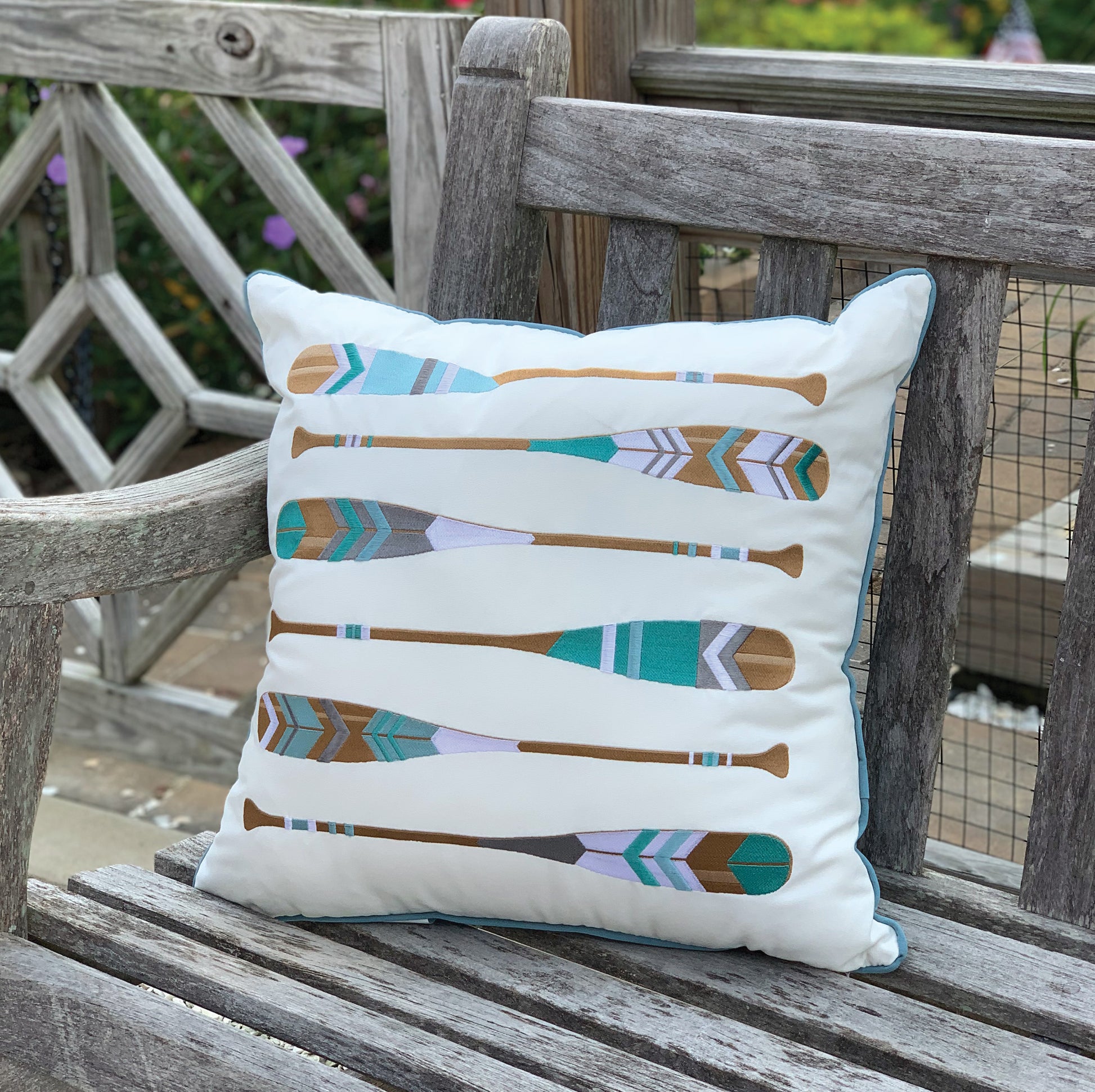 The Lake Oars Indoor Outdoor pillow styled on an outdoor bench.