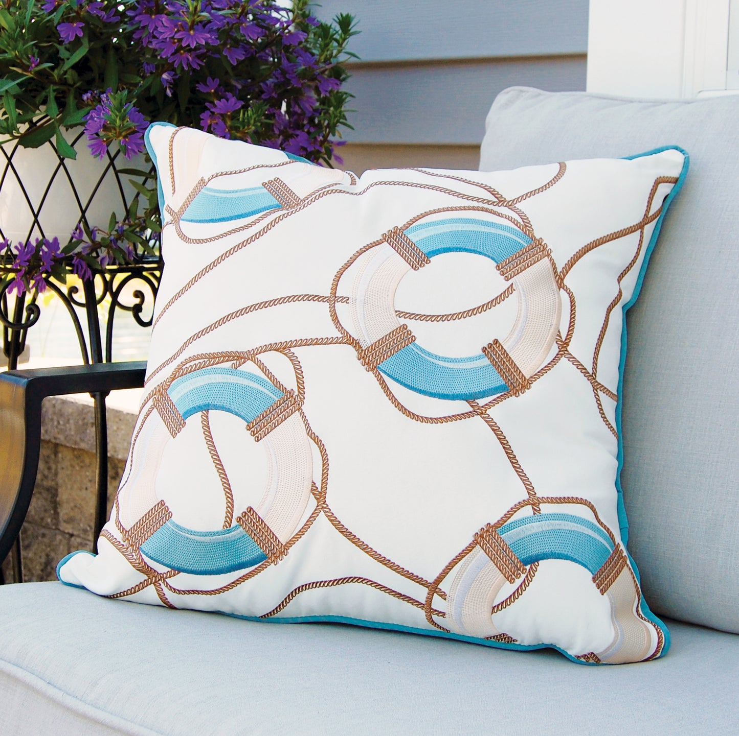 The Lake Preserver and Rope Outdoor Pillow is styled on an outdoor chair.