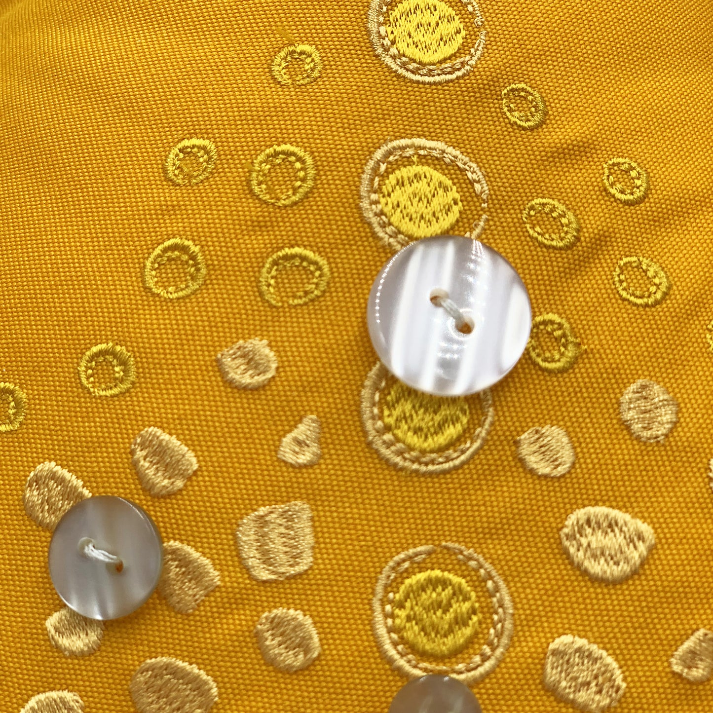 Detail shot of the embroidery work and beaded accents of the Marigold Sea Star Shaped Pillow.