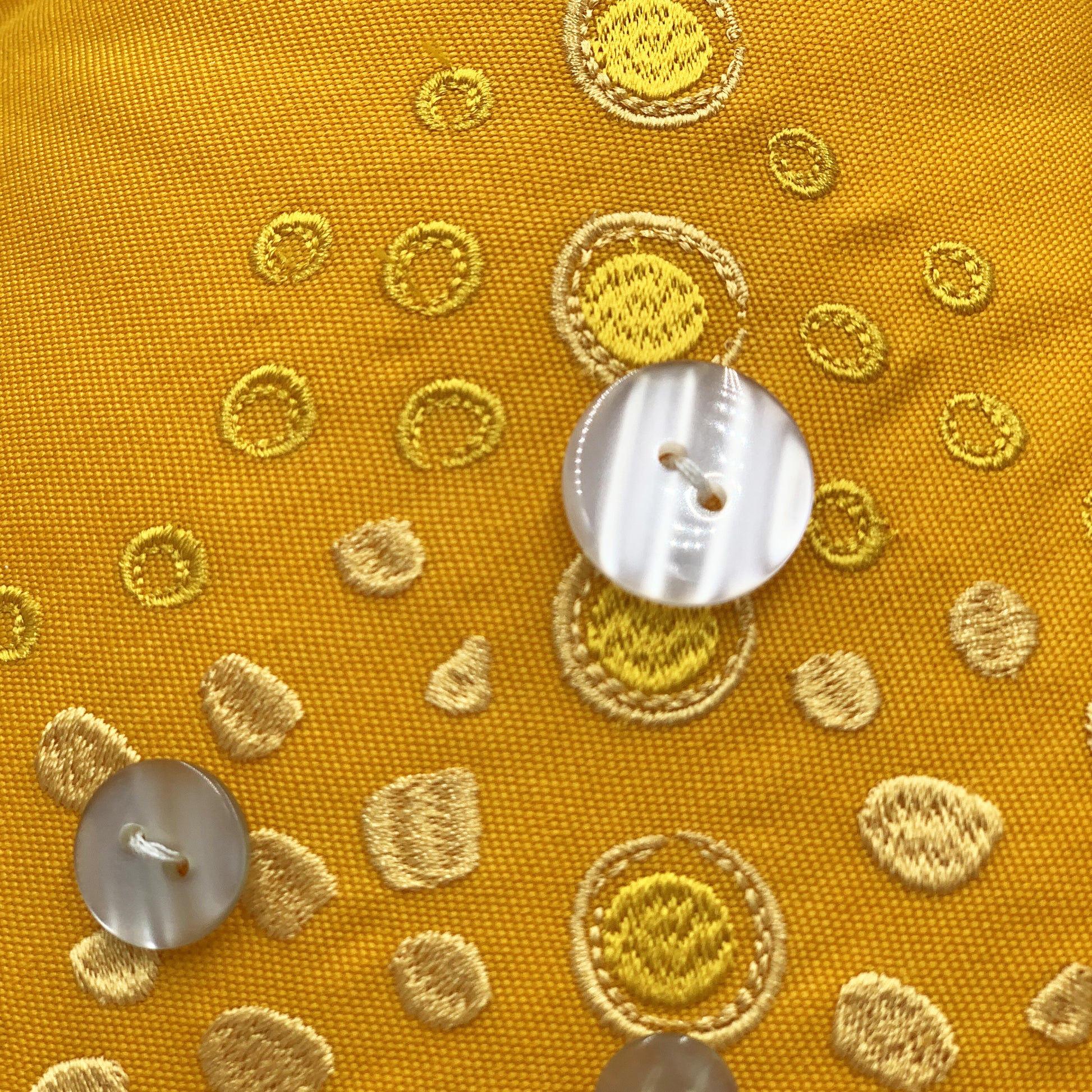 Detail shot of the embroidery work and beaded accents of the Marigold Sea Star Shaped Pillow.