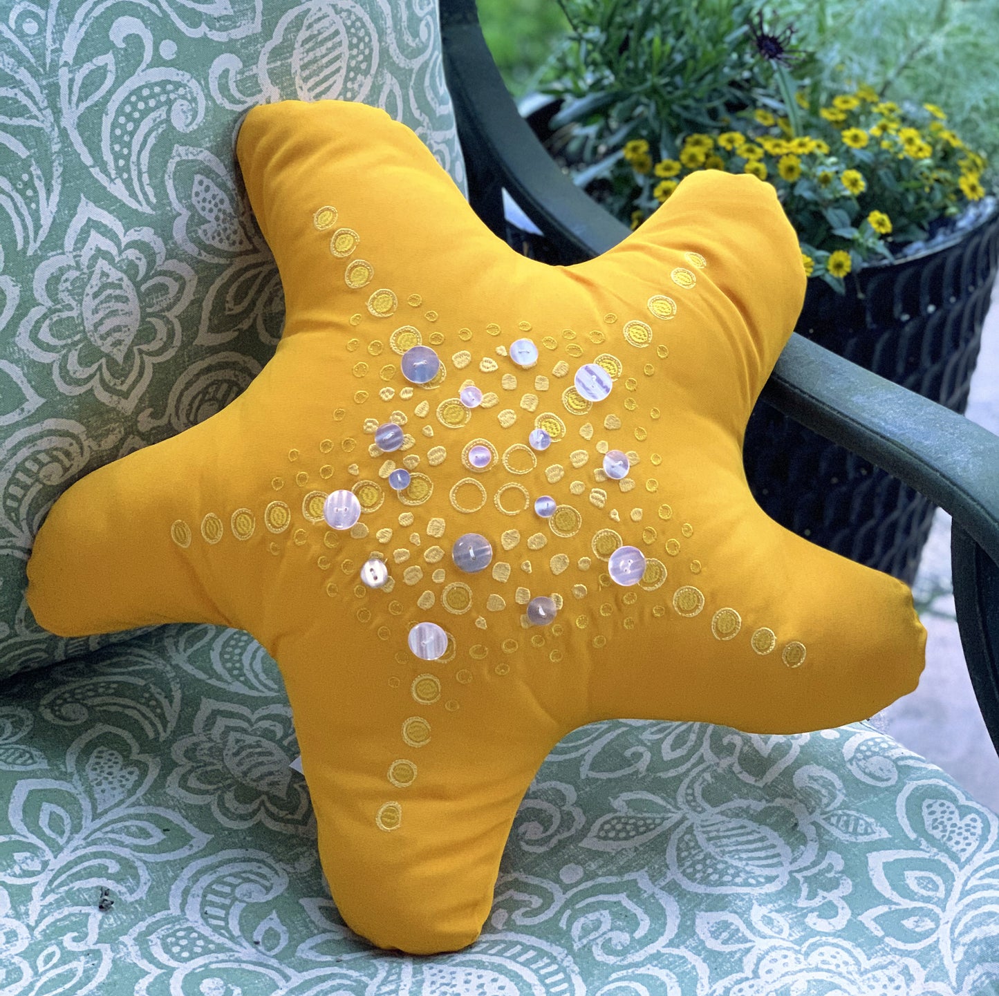 Marigold Shaped Sea Star pillow styled on an outdoor pillow.