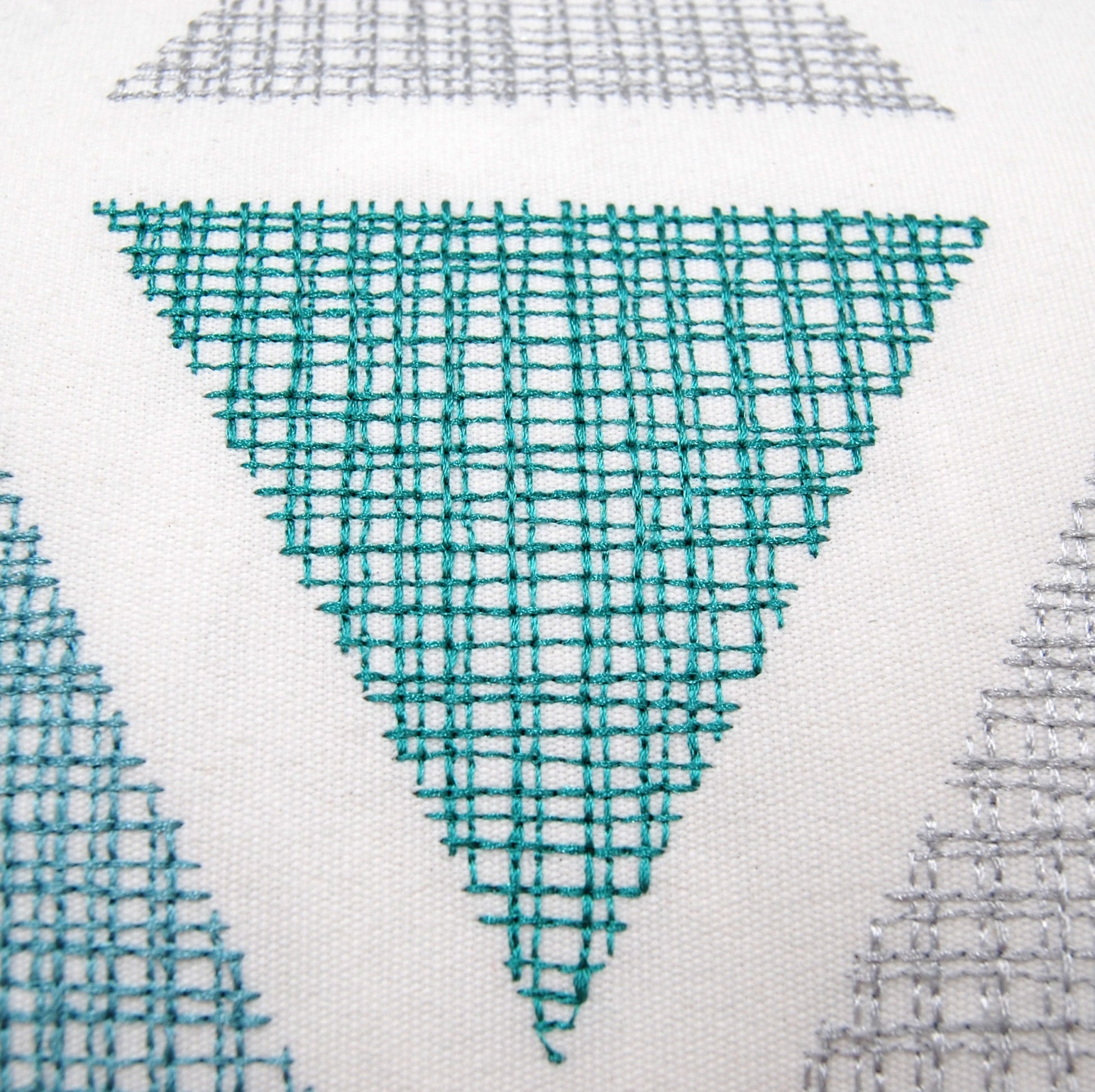 Detail shot of the Modern Lake Triangle Pillow's embroidery work.