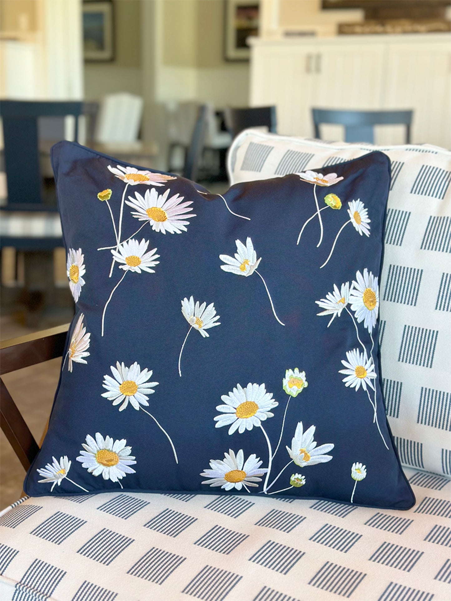 Navy Daisy Indoor Outdoor pillow styled on a chair.