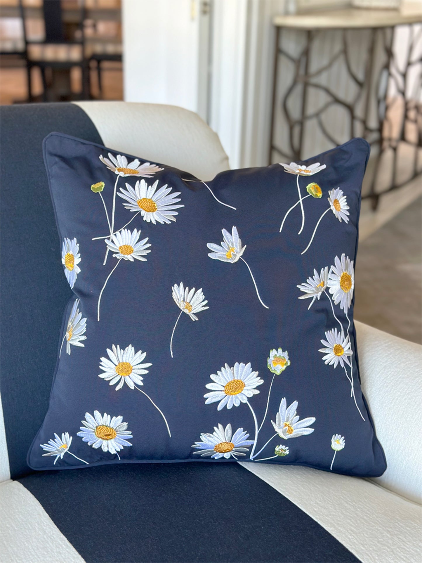 Navy Daisy Indoor Outdoor pillow styled on a chair.