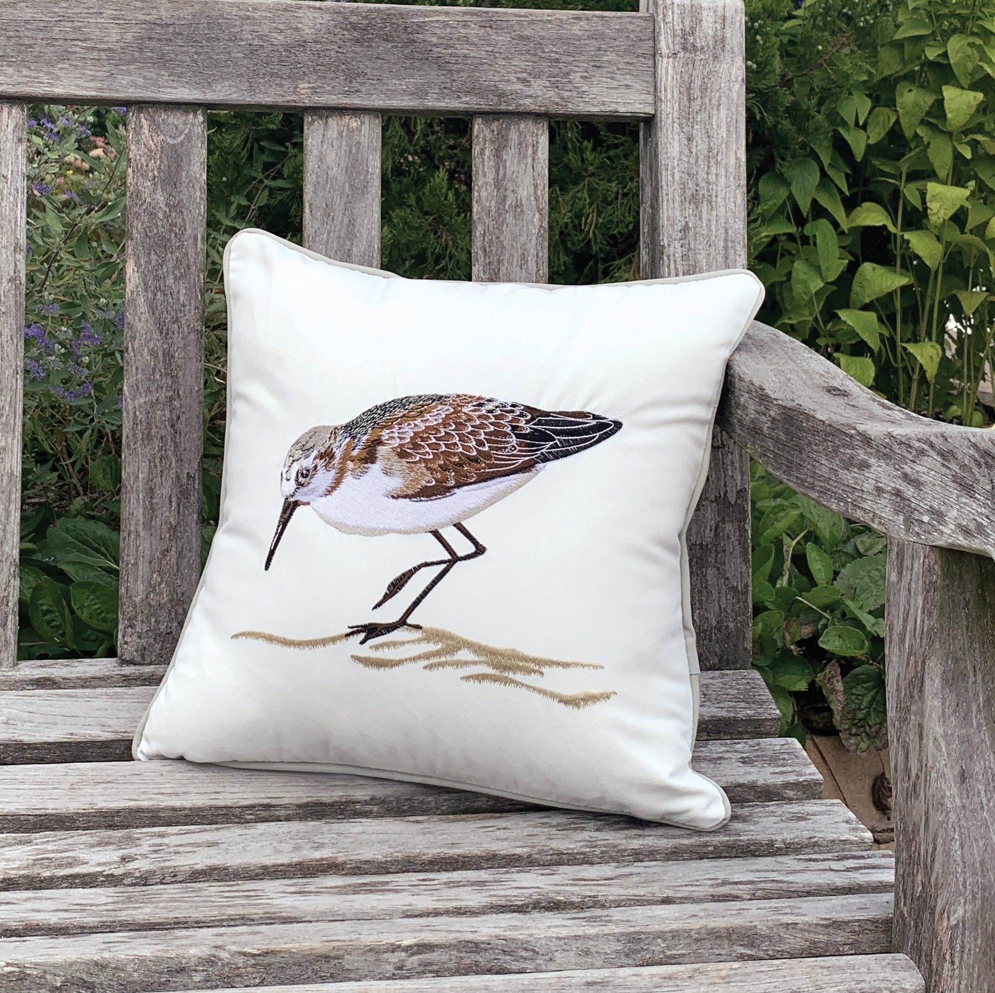 Sandpiper Chillin Left pillow styled on a garden bench.