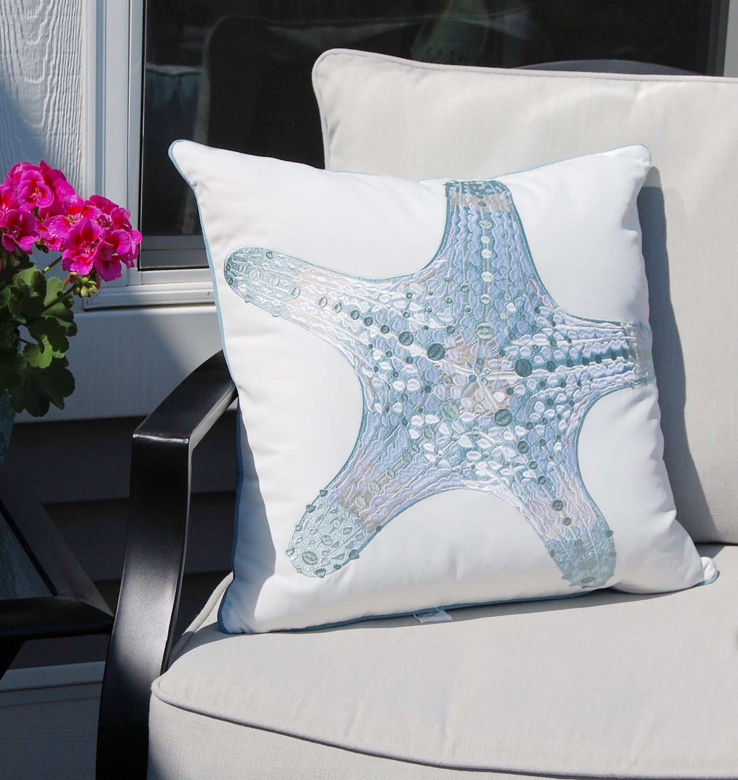 Sea Glass Sea Star outdoor pillow styled on a patio chair.