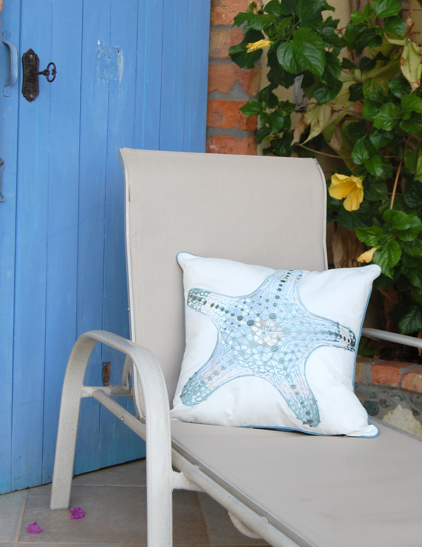 Sea Glass Sea Star Indoor Outdoor pillow styled on a lounge chair.