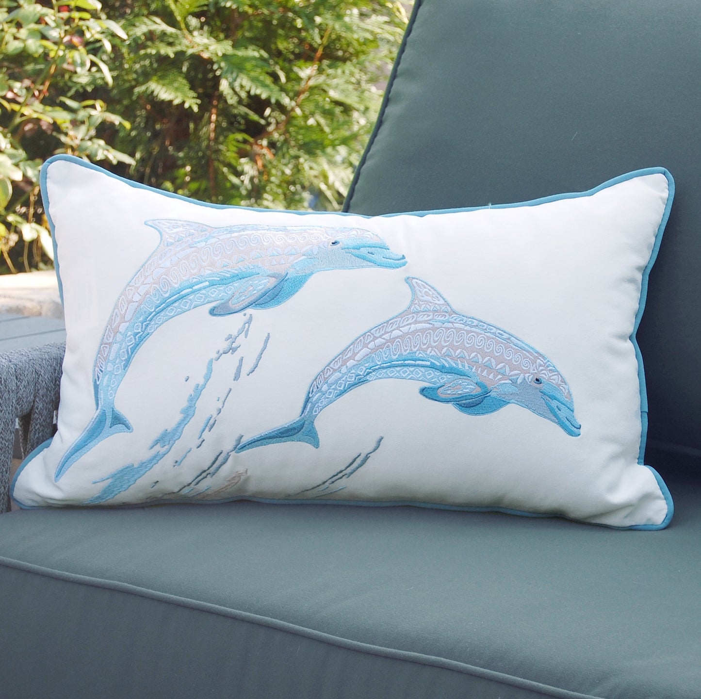 Sea Glass Tribal Dolphin Indoor Outdoor Pillow styled on a patio chair.