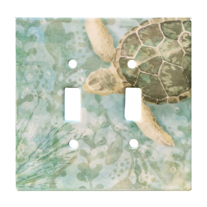 ceramic green double toggle switch plate featuring seaweed patterns and a green sea turtle swimming in from the top right corner.