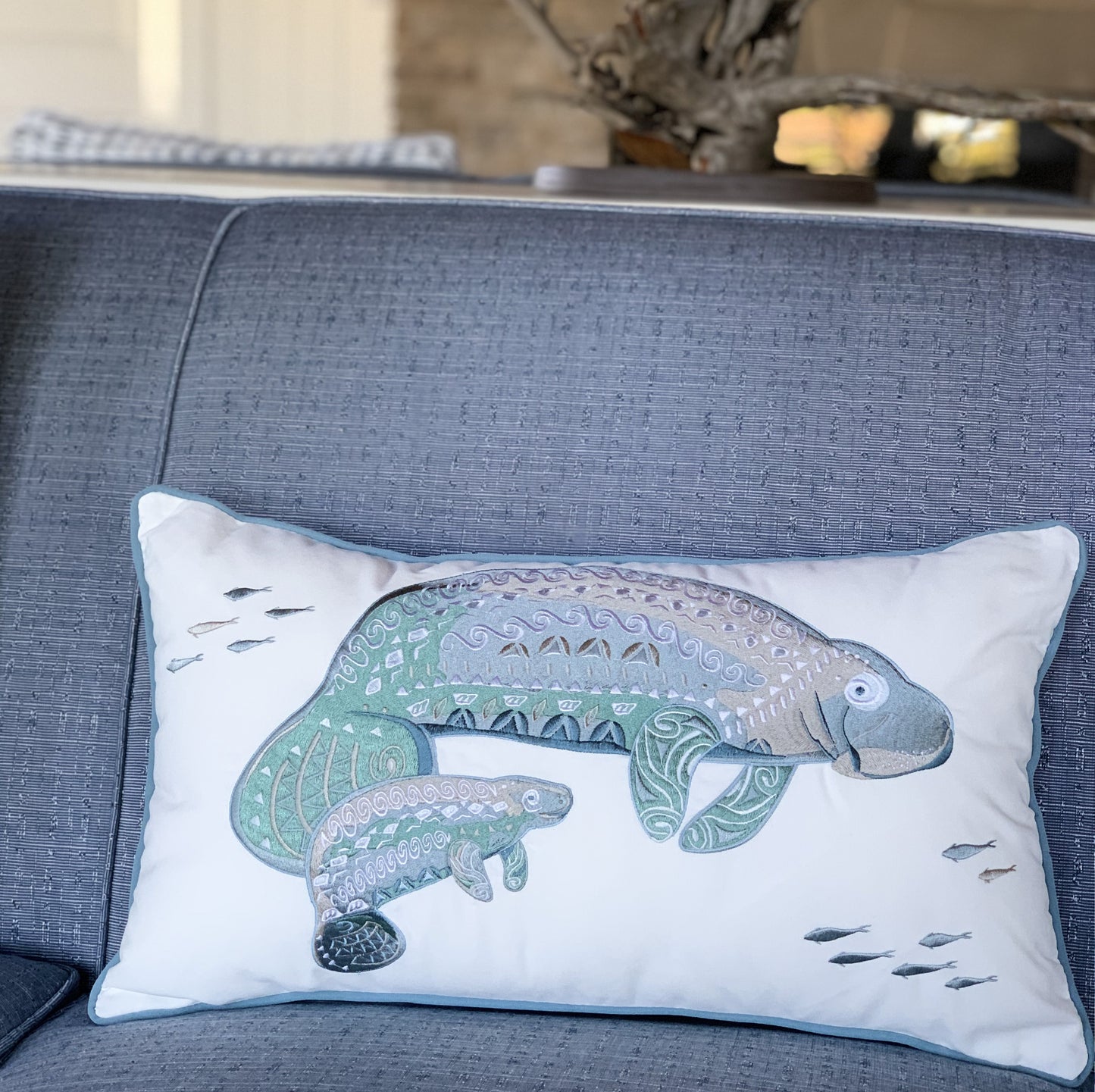 Seaglass Tribal Manatee Indoor Outdoor Pillow styled on an indoor couch.