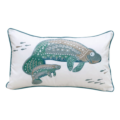 A mother and baby manatee featuring tribal designs is embroidered on a white background. Pillow is finished with blue piped edging.