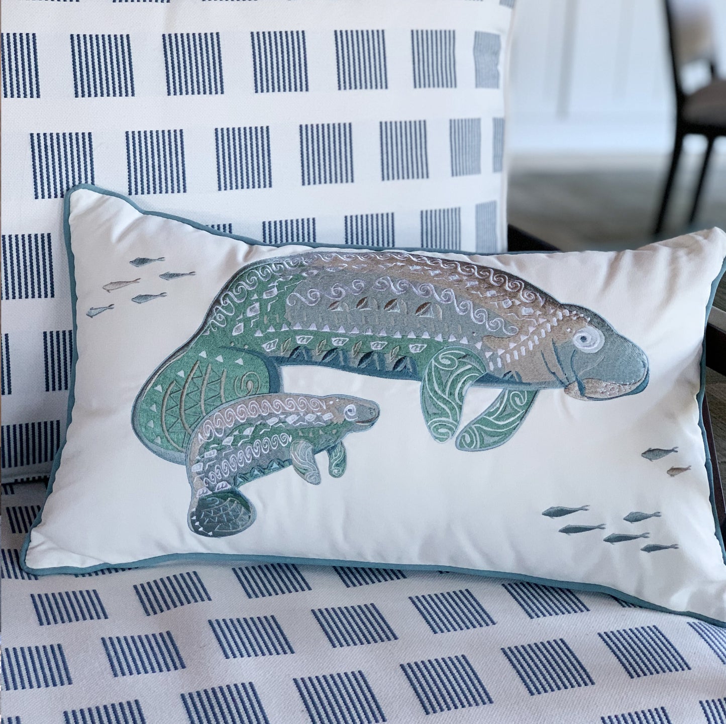 Seaglass Tribal Manatee Indoor Outdoor Pillow styled on a patio chair.