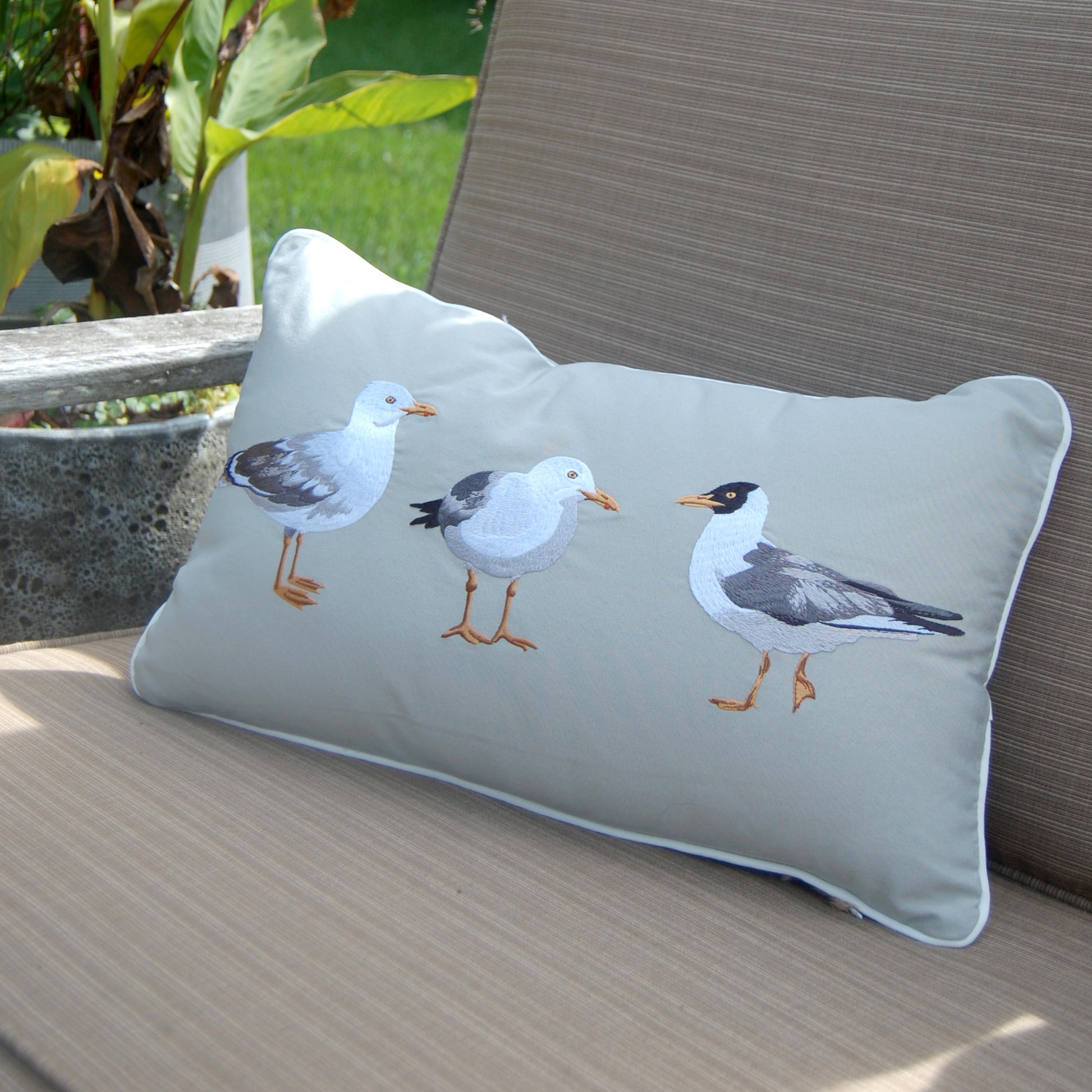 Seagull Flash Mob Lumbar Indoor Outdoor pillow styled on a lounge chair.
